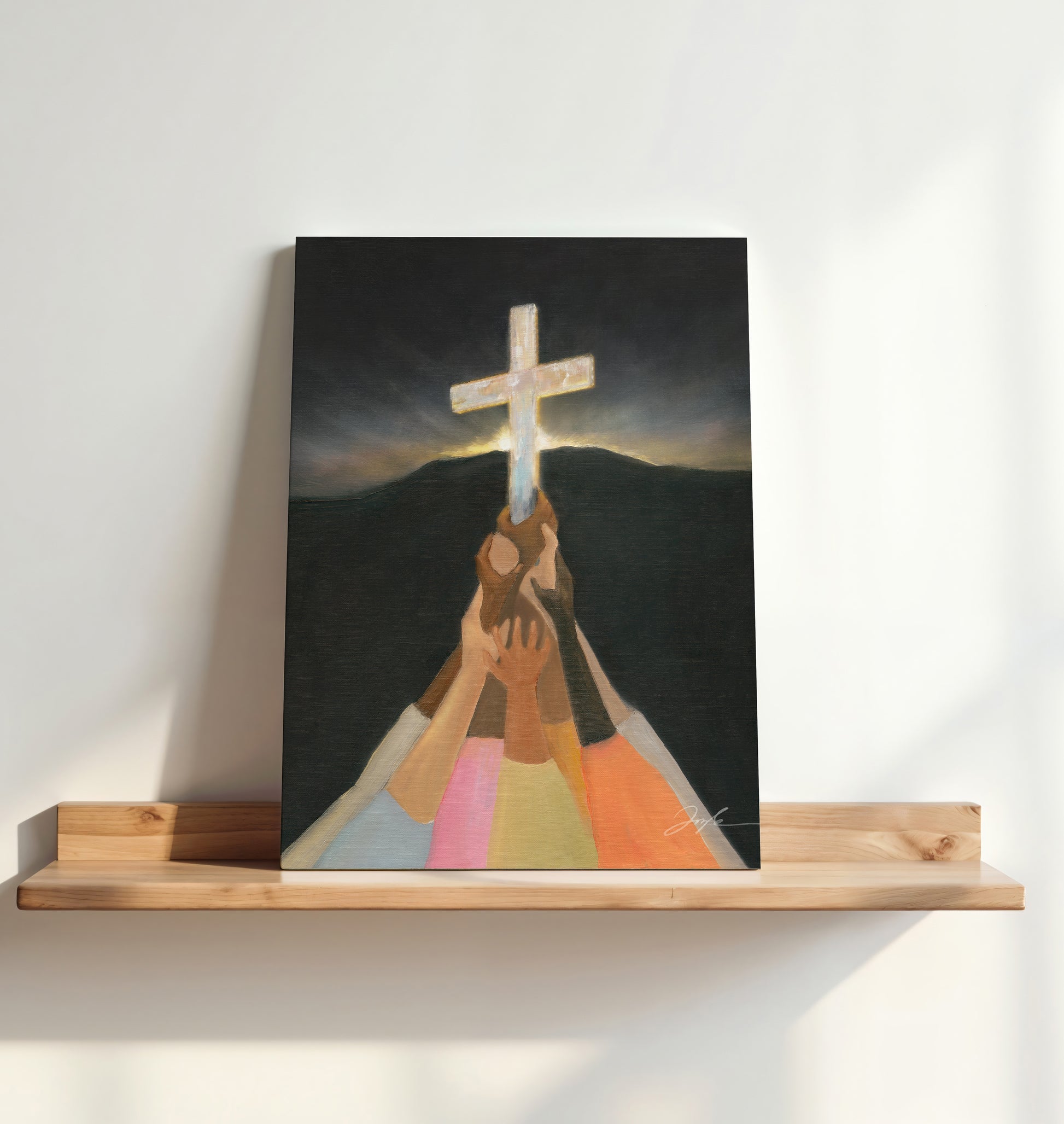 Painting of hands holding a cross against a mountainous background on a wooden shelf.