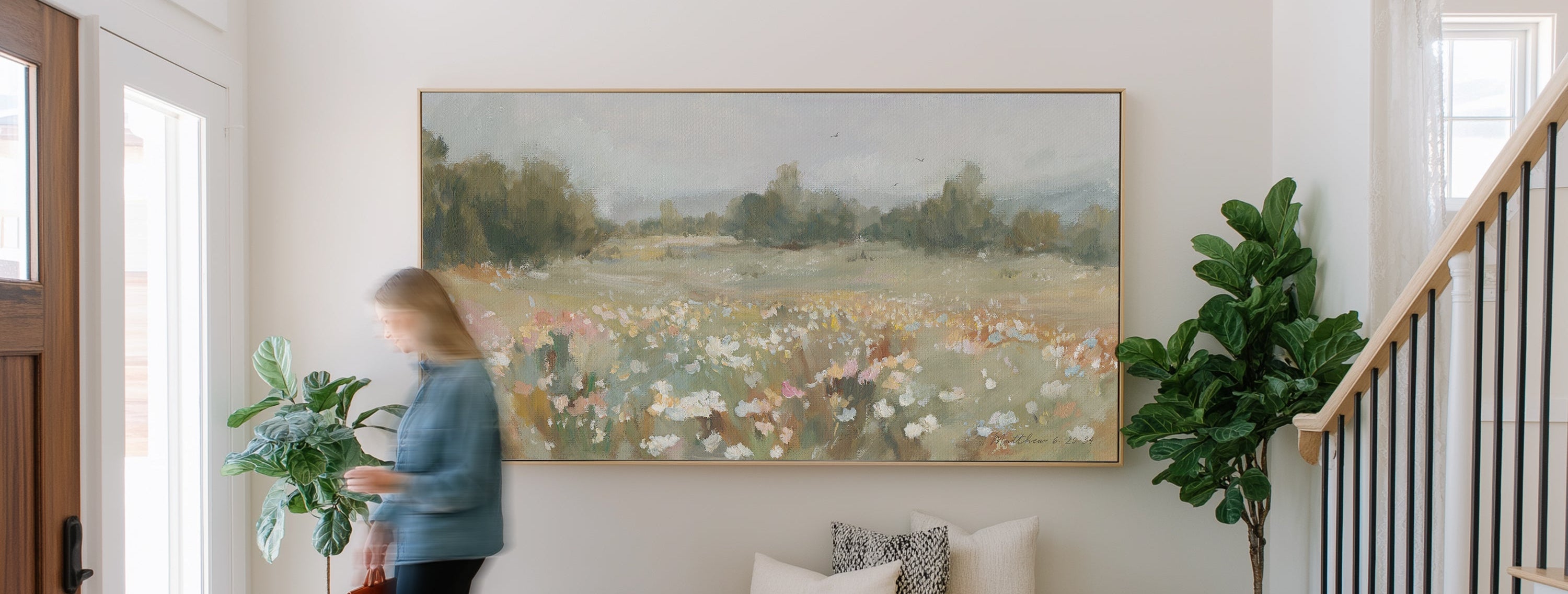 A large statement piece painting of a peaceful wildflower field landscape on the entry way wall.