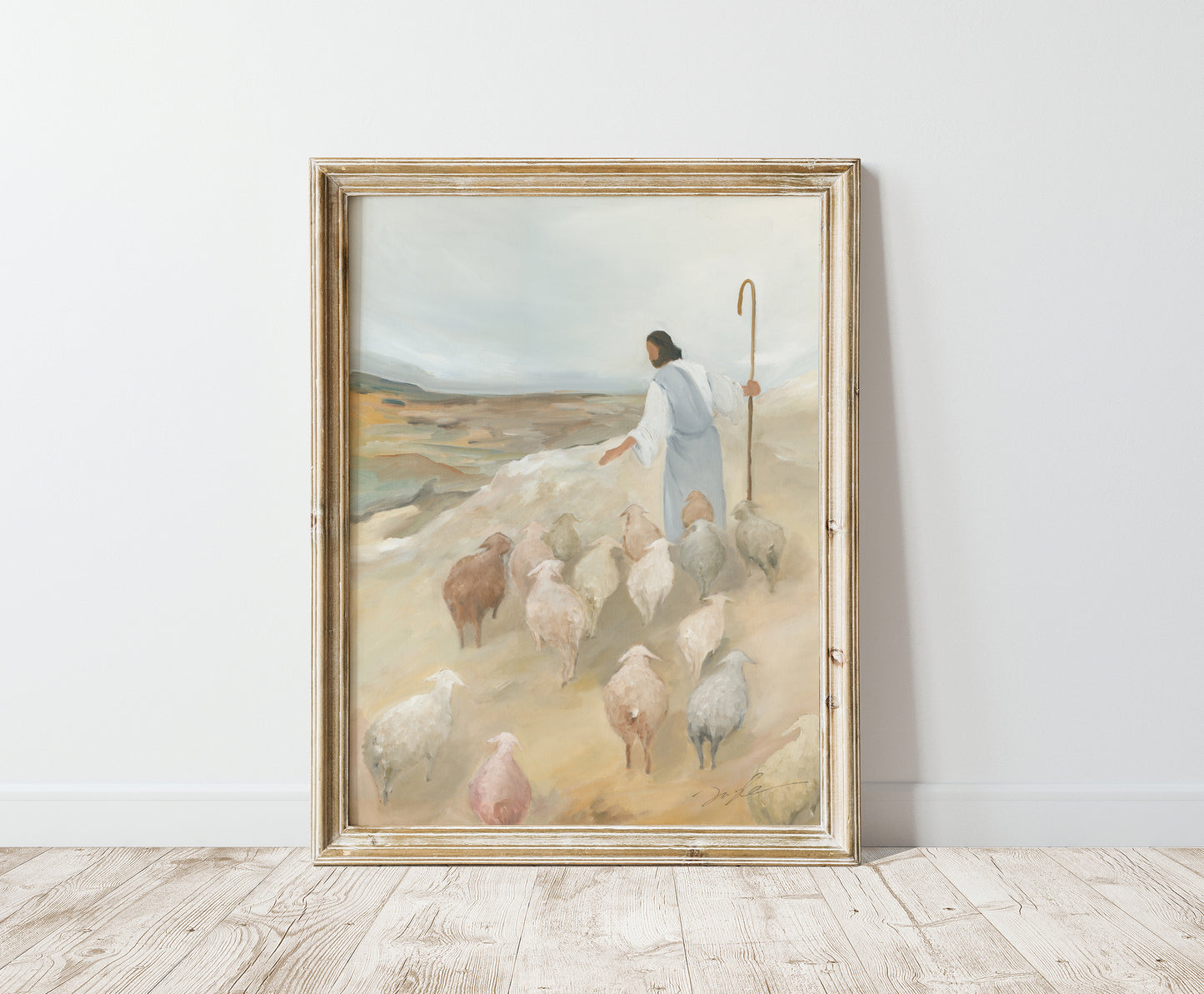 The Good Shepherd painting in a distressed gold frame, leaning against a light wall on a wooden floor.