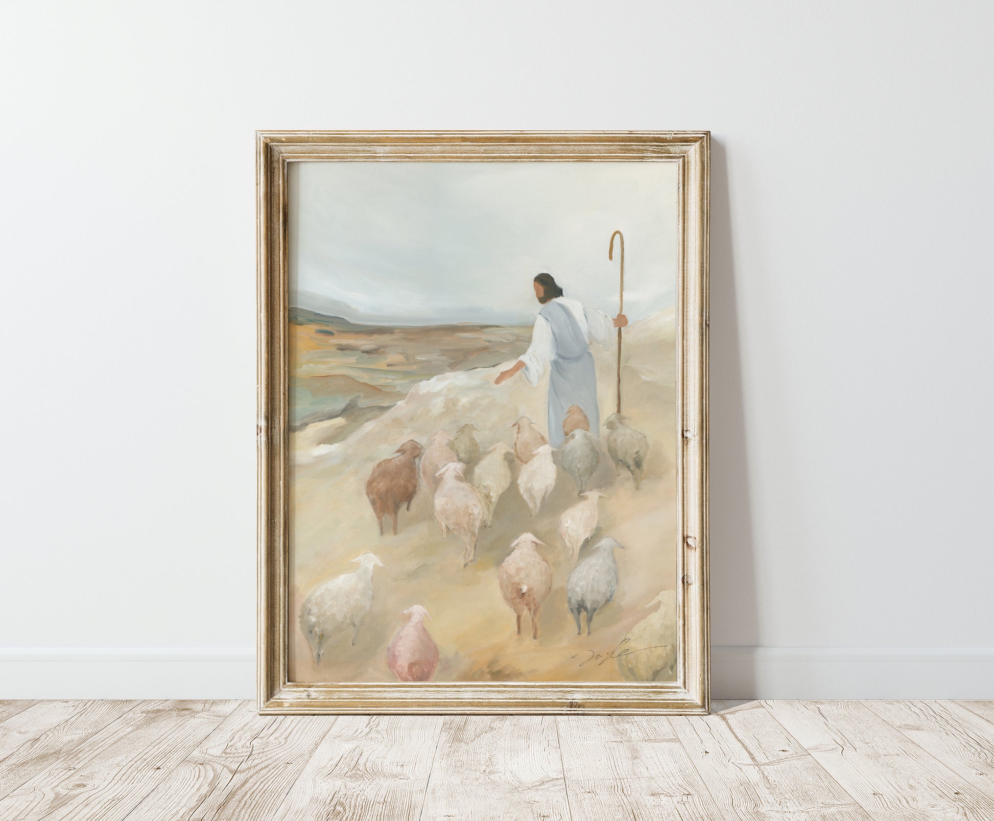 The Good Shepherd painting in a distressed gold frame, leaning against a light wall on a wooden floor.
