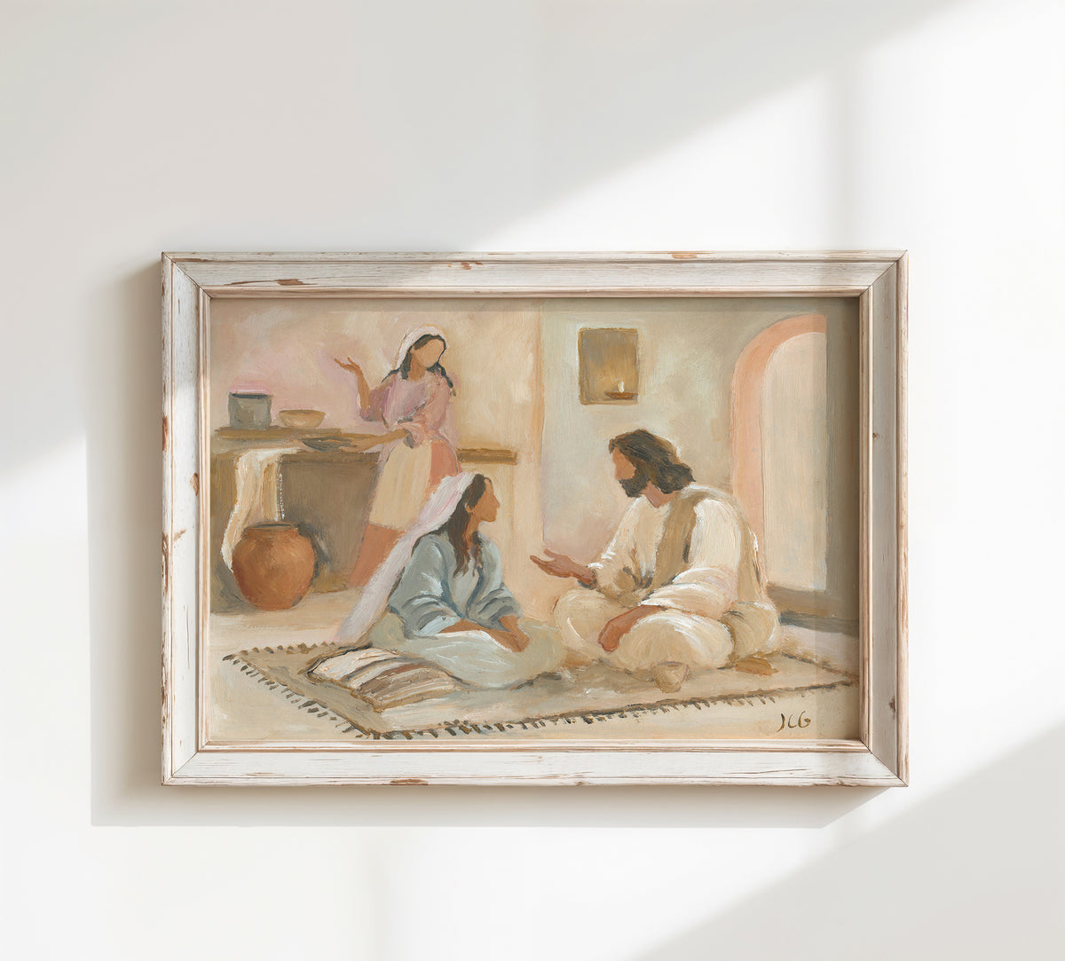 A framed painting on a white wall, depicting a biblical scene of Mary and Martha with Jesus showing Mary seated at Christ’s feet while Martha serves in the background.